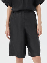 A lady wears a black shorts made of silk.
